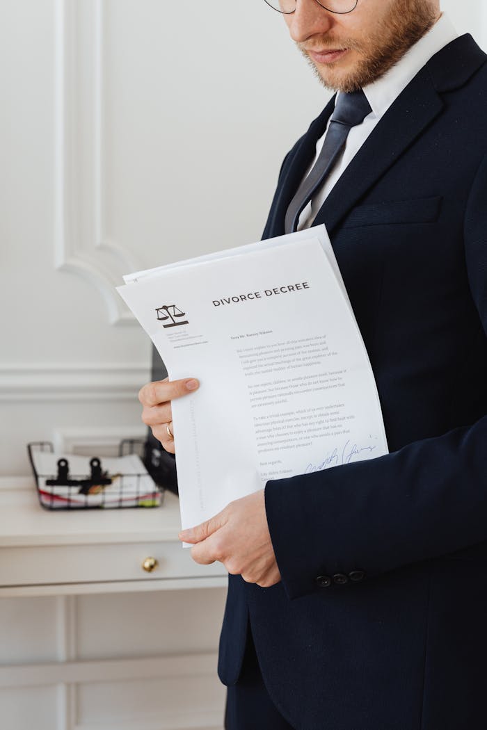 Close-up of a suited professional holding a divorce decree document indoors.
